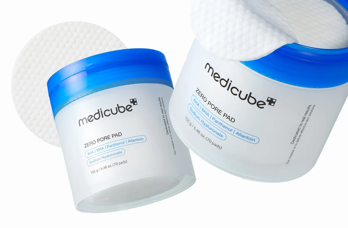 medicube Zero Pore Pad — frosted jars with blue lids and a round textured pad, labelled AHA, BHA, Panthenol, Allantoin and Sodium Hyaluronate