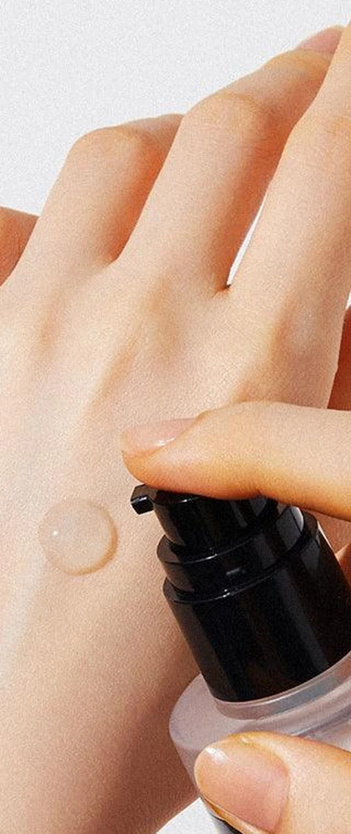COSRX Advanced Snail 96 Mucin Power Essence, a frosted bottle with a black pump, beside a clear, glossy drop of the essence on the back of a hand